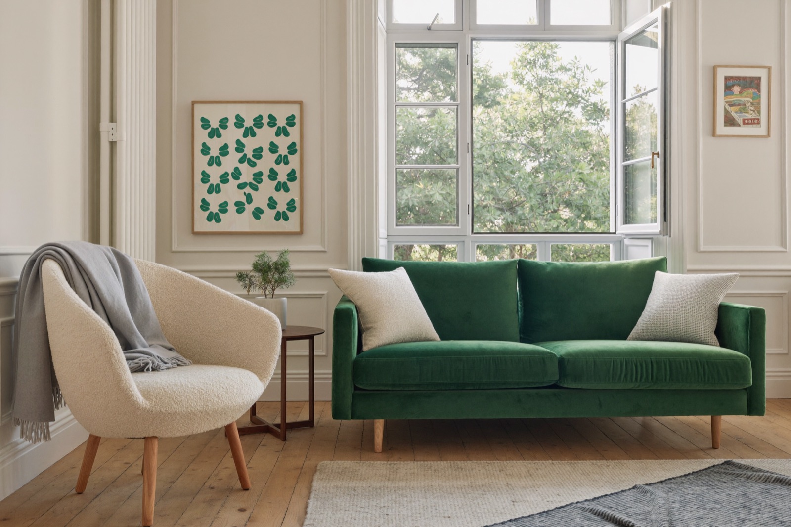 Beżowy fotel boucle i butelkowozielona sofa welurowa w jasnym, zadbanym salonie